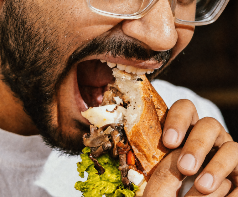 Man biting into a large sandwich, illustrating jaw fatigue while chewing